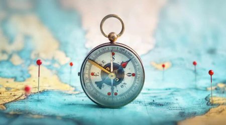 Magnetic compass  and location marking with a pin on routes on world map. Adventure, discovery, navigation, communication, logistics, geography, transport and travel theme concept background.. Macro photo. Very shallow focus.